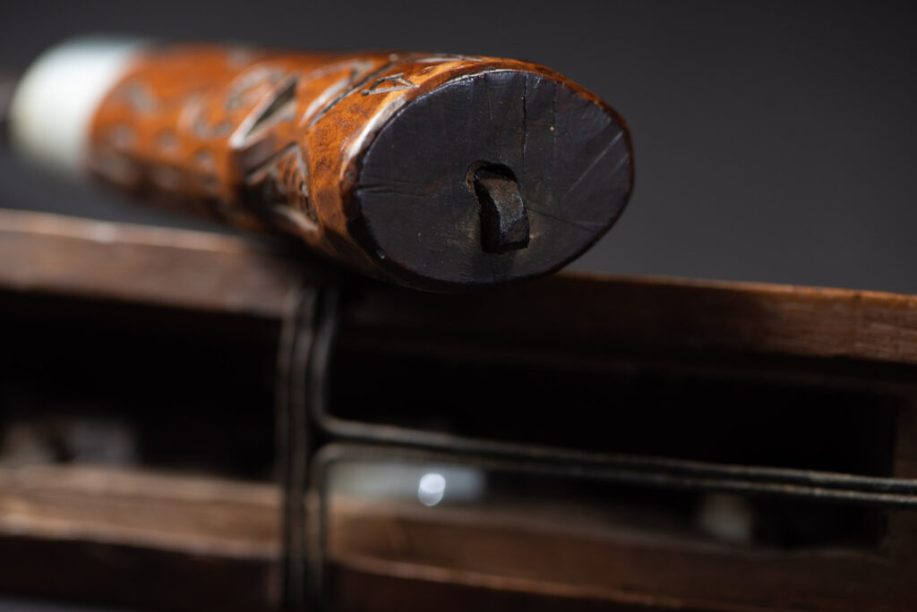 Very fine old sword from the Paiwan tribe, with a scabbard carved with multiple human faces. One side is inlaid with three faience circles.