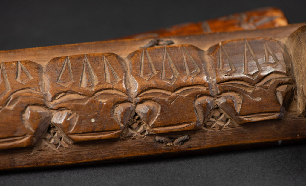 Very fine old sword from the Paiwan tribe, with a scabbard carved with multiple human faces. One side is inlaid with three faience circles.