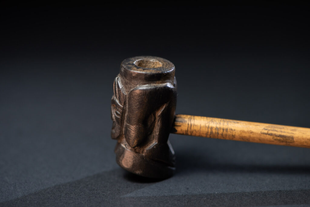 Very fine pipe made of precious wood from the Paiwan tribe, carved with human faces representing a Paiwan warrior and a stylised deer. The bottom is carved in a deer hoof shape.