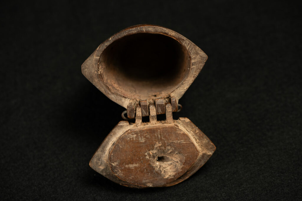 Wooden belt snuffbox from the Pingpu tribes, decorated with an engraving of a Chinese sage. It features a hinged lid carved from a single piece of wood and a section designed for attachment to the belt.