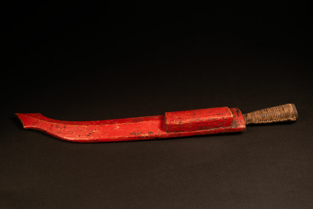 This small sword is not carved but simply painted red. It likely belonged to a farmer.