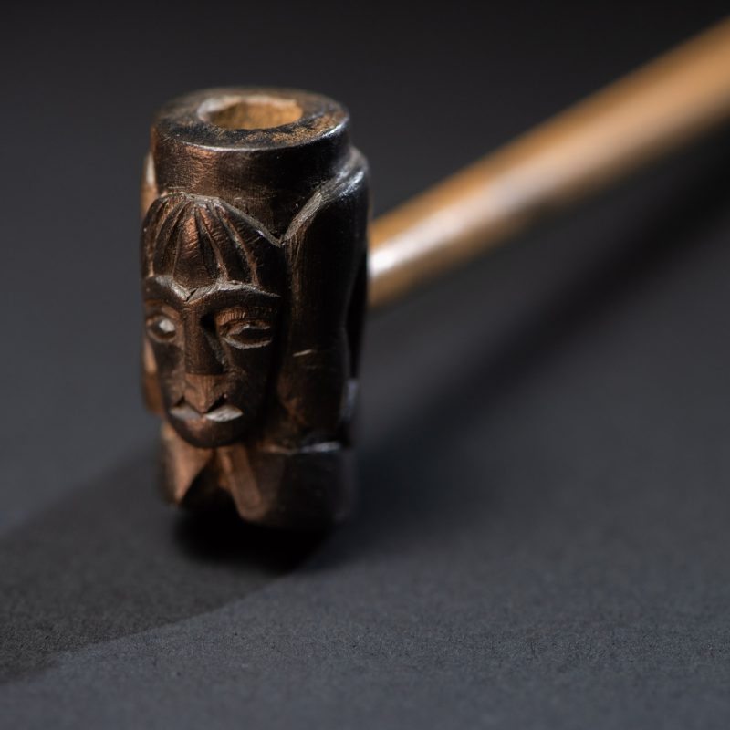 Very fine pipe made of precious wood from the Paiwan tribe, carved with human faces representing a Paiwan warrior and a stylised deer. The bottom is carved in a deer hoof shape.