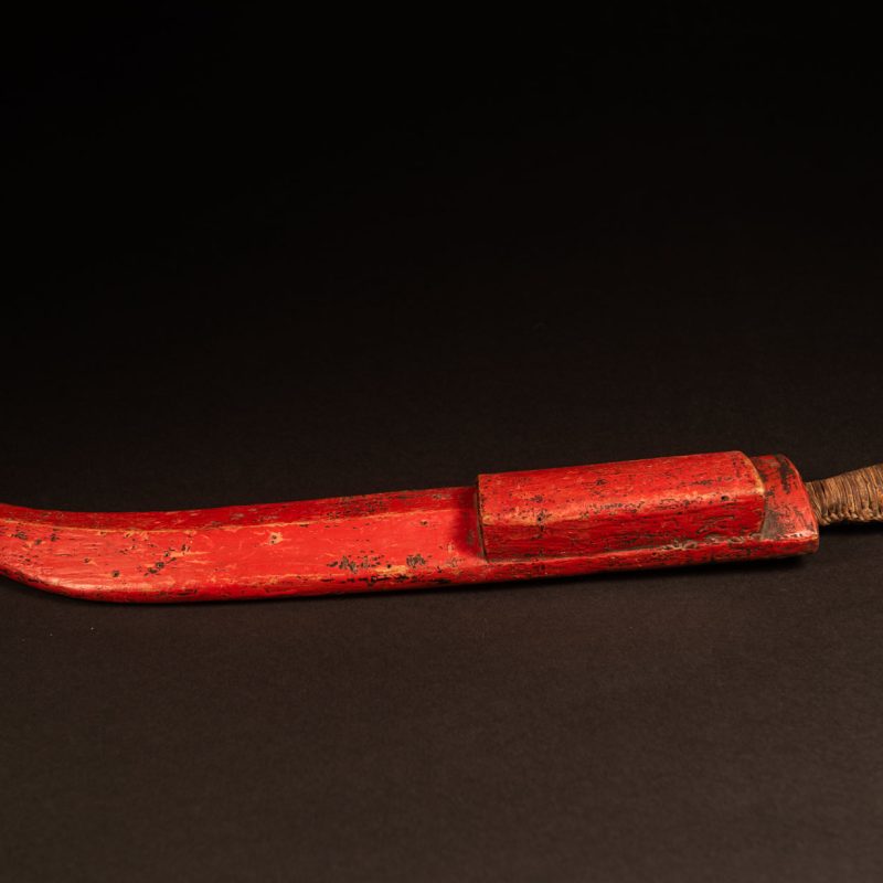 This small sword is not carved but simply painted red. It likely belonged to a farmer.