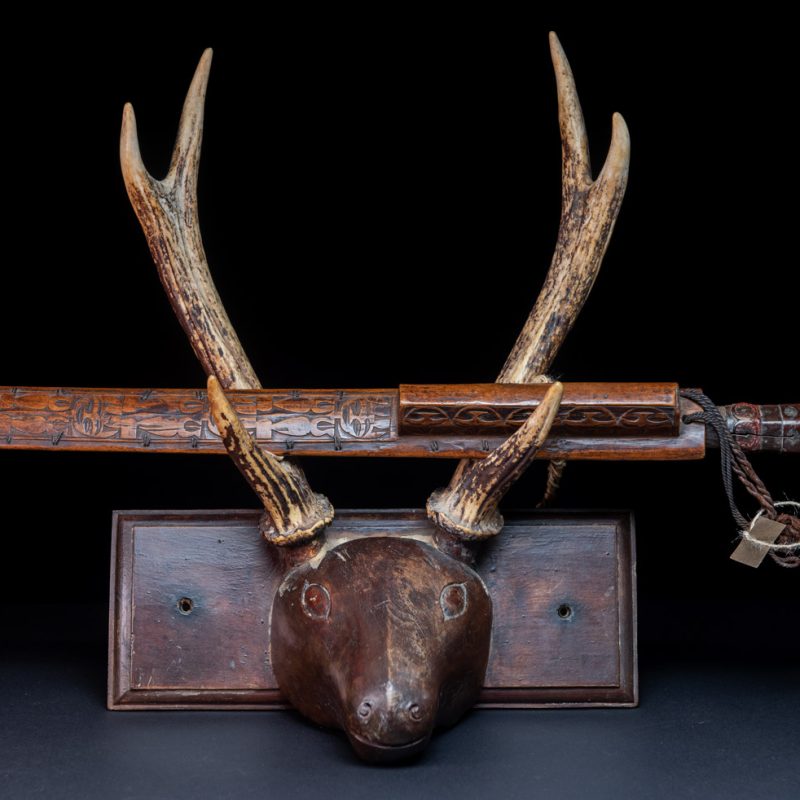 Very fine ceremonial sword from the Paiwan tribe, featuring a sheath carved with full-standing ancestral figures and a handle tinted with red pigment. The sides are carved with human faces.