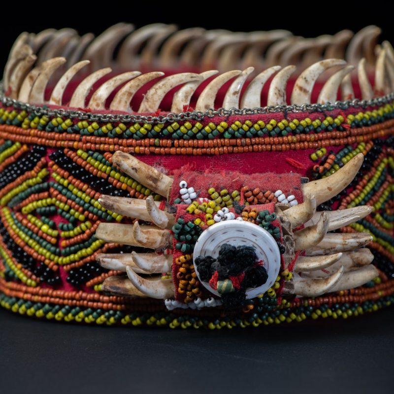 Women's headdress from the Paiwan tribe, made of green, yellow, red, and black beads arranged in geometric patterns, and topped with boar tusks.